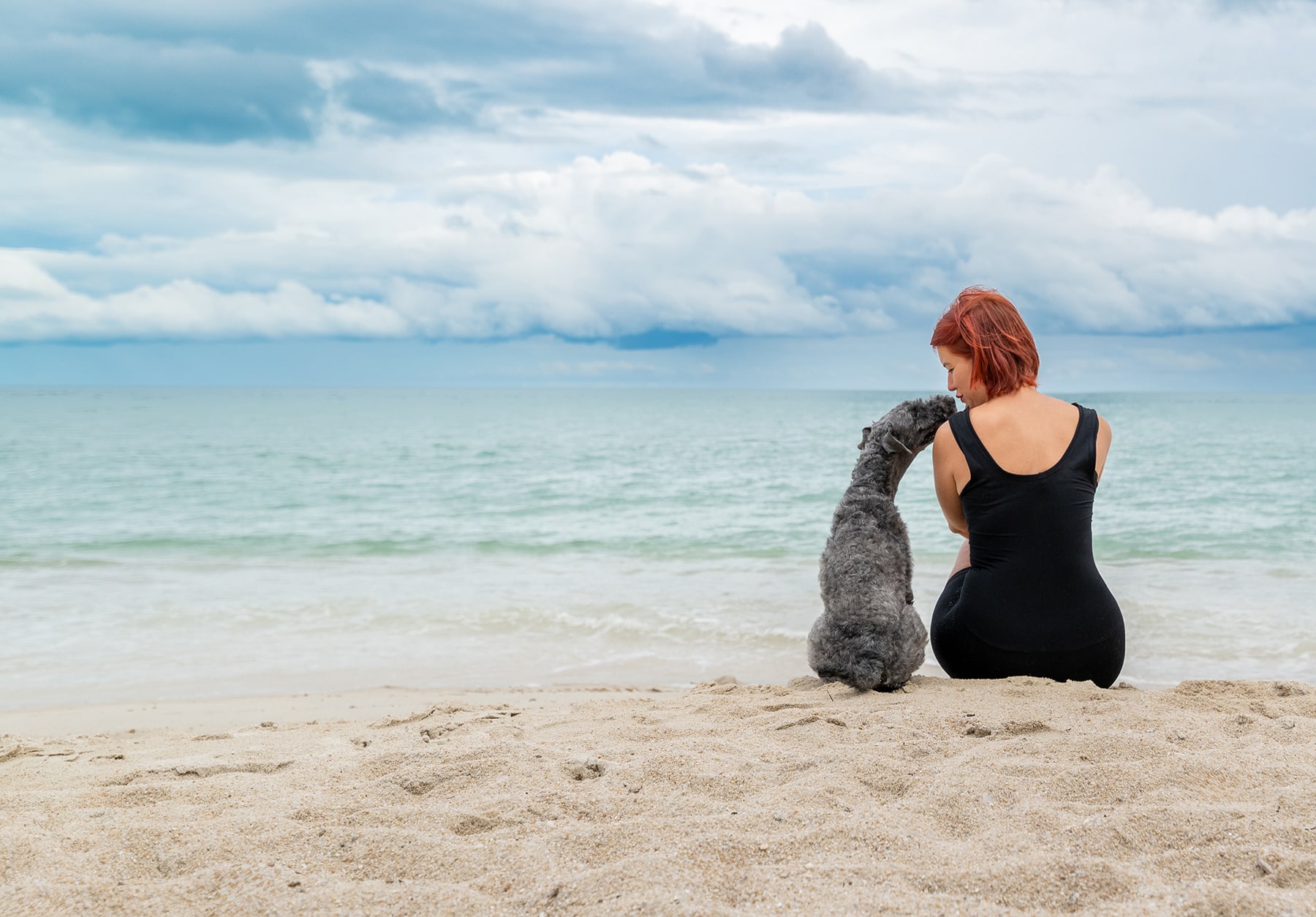 Valeria Nikitina sits on the beach with the dog